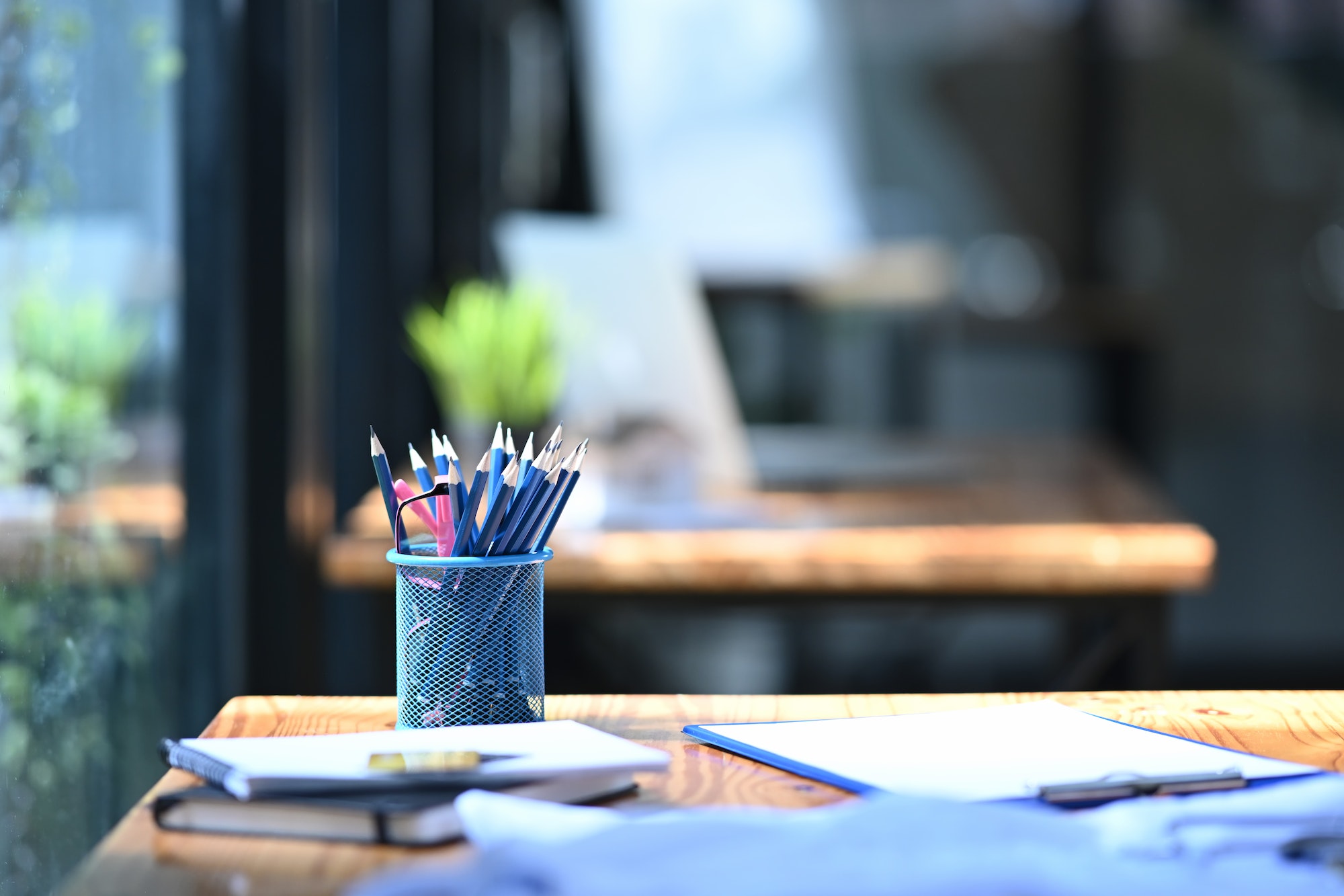 Pencil holder, books and financial documents on wooden table in office.